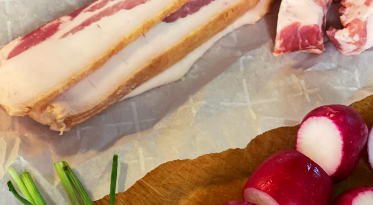 bacon, radishes and green onion on a piece of parchment paper on a tan cutting board for the keto on the rise blog post wilted lettuce salad with hot bacon dressing