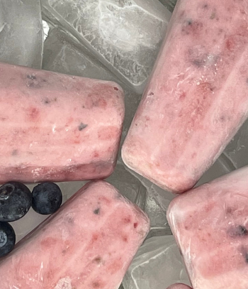 photo of whole berry keto popsicles on a tray of ice with blueberries and strawberries on the tray of ice around the popsicles for the blog keto on the rise blog post keto whole fruit summer berry popsicles